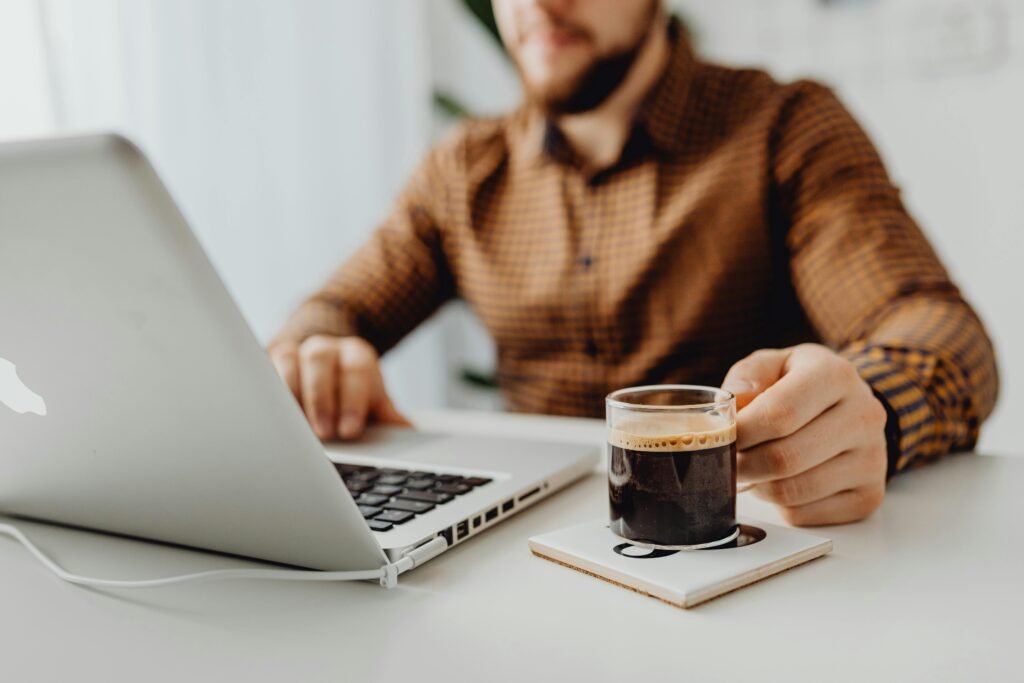 Man in front of a computer holding a cup of coffee.